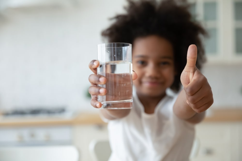 child holding high quality water with thumbs up