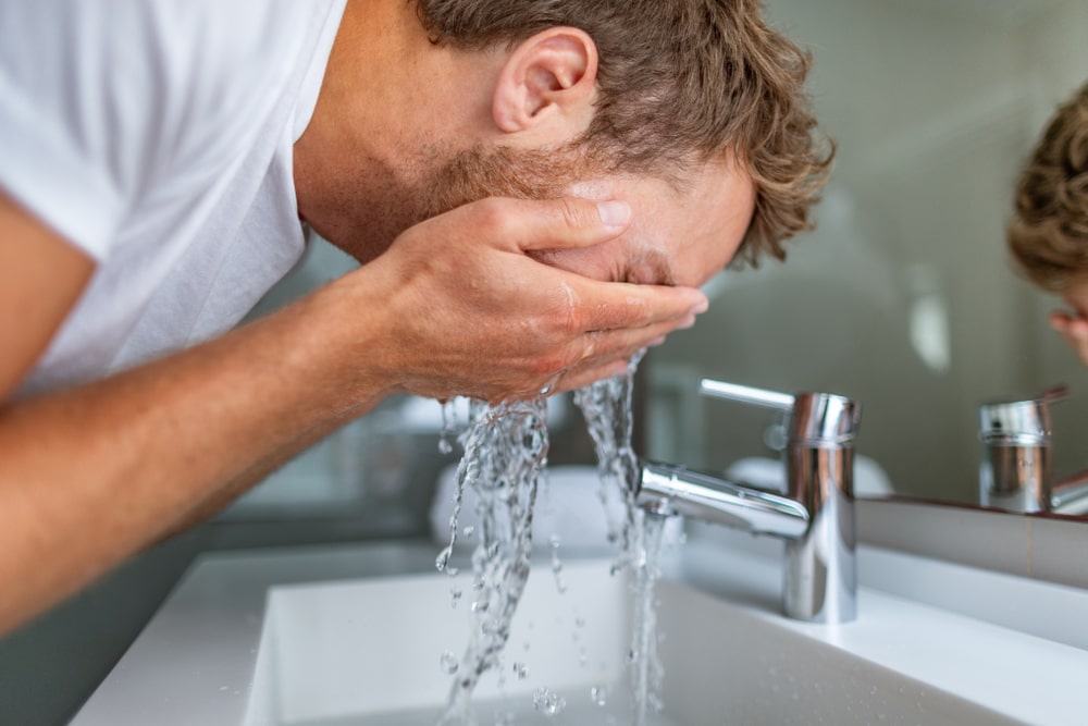 man washing his face with soft water